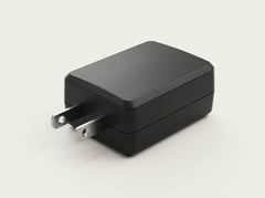 A black rectangular wall charger adapter with a two-prong US plug, shown on a clean off-white background.